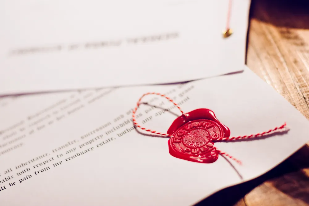 A red wax seal and string on the corner of a document ready for legalisation